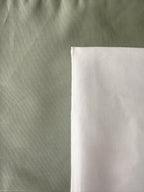 Two fabric swatches shown side by side, one in a muted sage green and one in a clean white, with the green swatch occupying the majority of the frame.